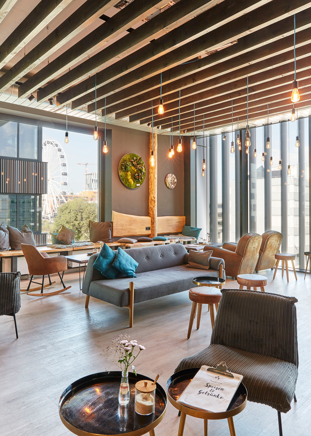 Foto: Modern gestalteter Aufenthaltsbereich mit Lounge-Möbeln, Decke aus Holzlamellen, dunklen Wänden und großzügiger Verglasung in wohnlicher Atmosphäre.
