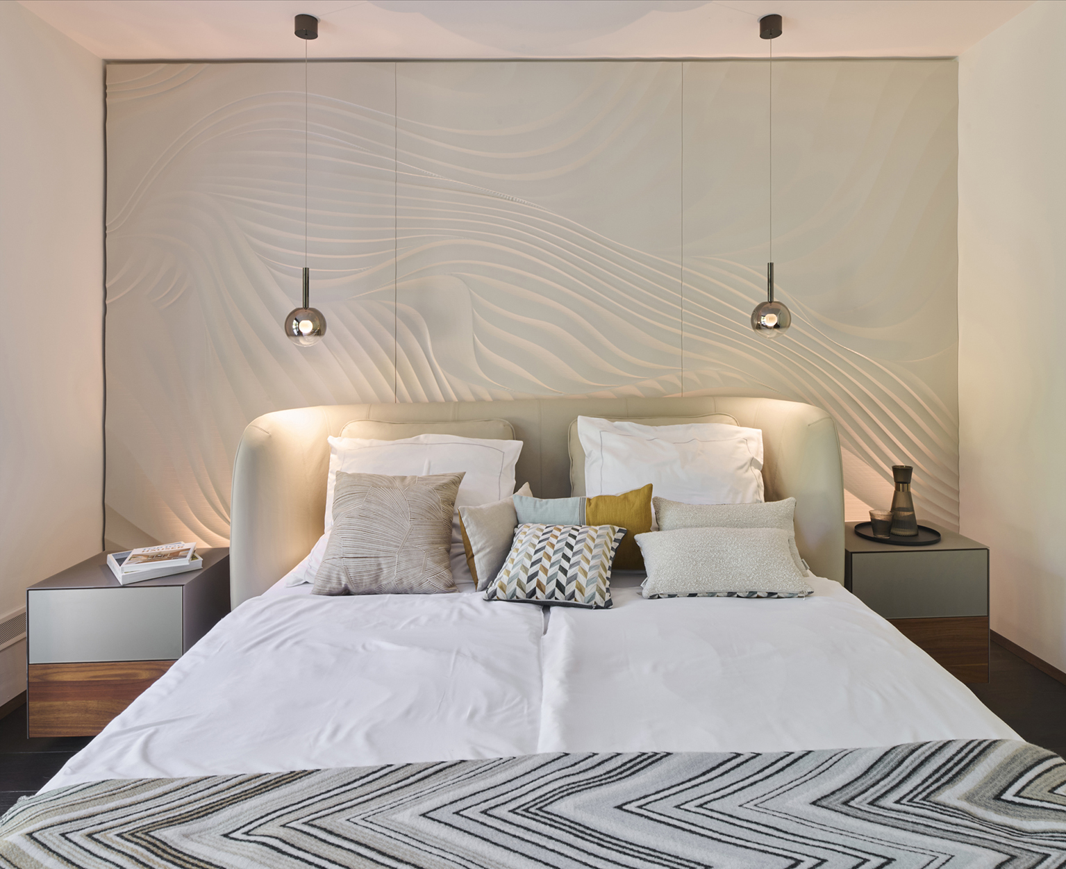 Foto: Modernes Schlafzimmer mit Bett aus hellem Leder, runde Glas-Pendelleuchten und weißen 3D-Wandpaneelen mit Wellen Optik.