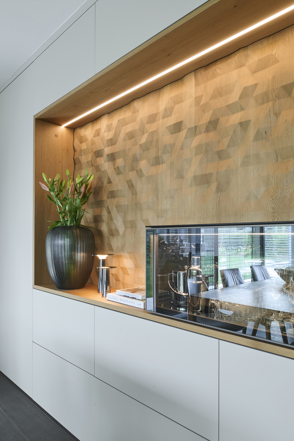 Foto: Moderne, weiße Schrankwand mit eingesetzter Holzvertäfelung in geometrischem Muster, indirekter Beleuchtung und integrierter Vitrine.