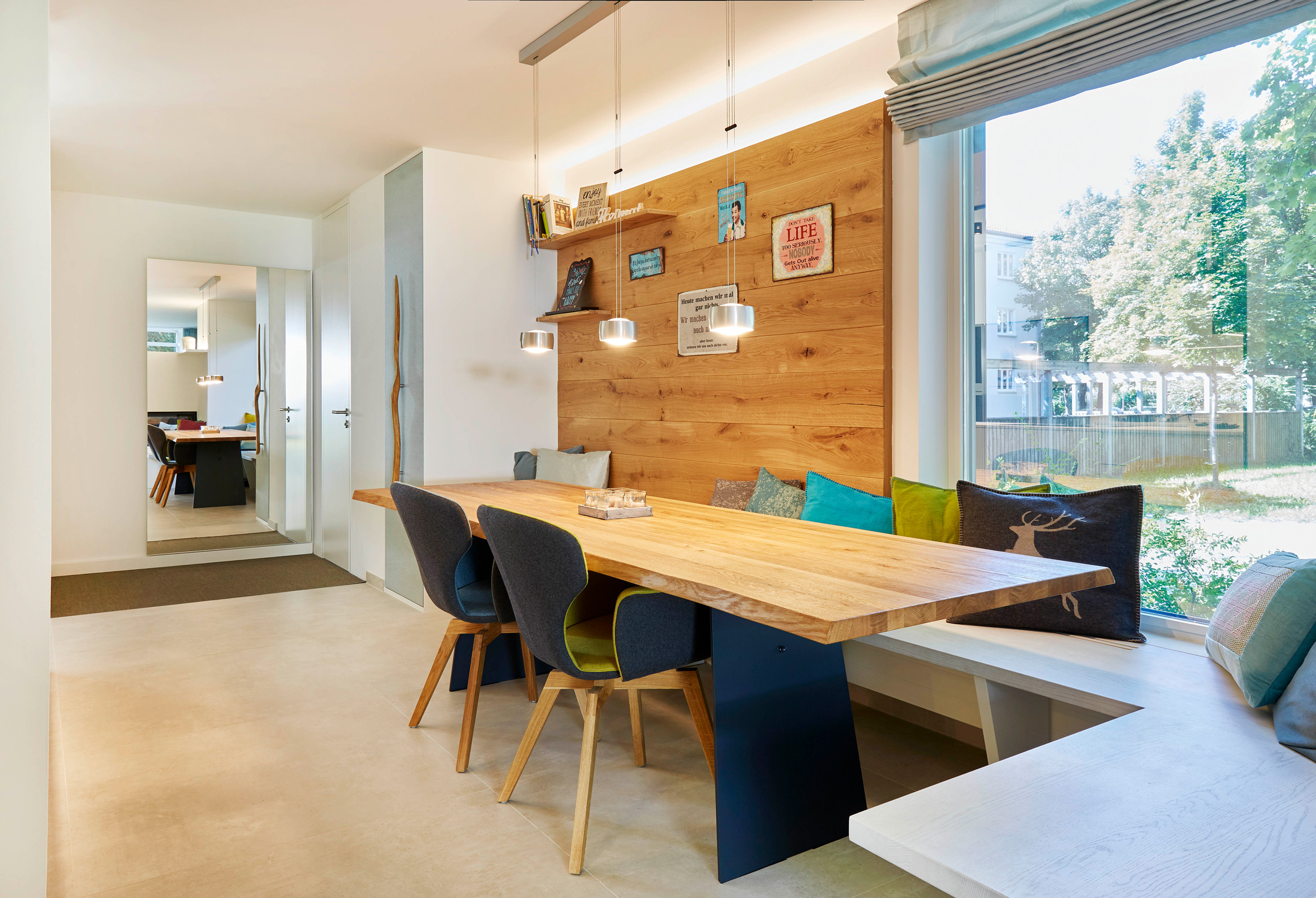 Foto: Modern, rustikaler Essbereich mit Esstisch und Rückwand aus Holz, Filz-Stühlen, Pendelleuchten und Einbau-Sitzbank mit Kissen vor Fensterfront.