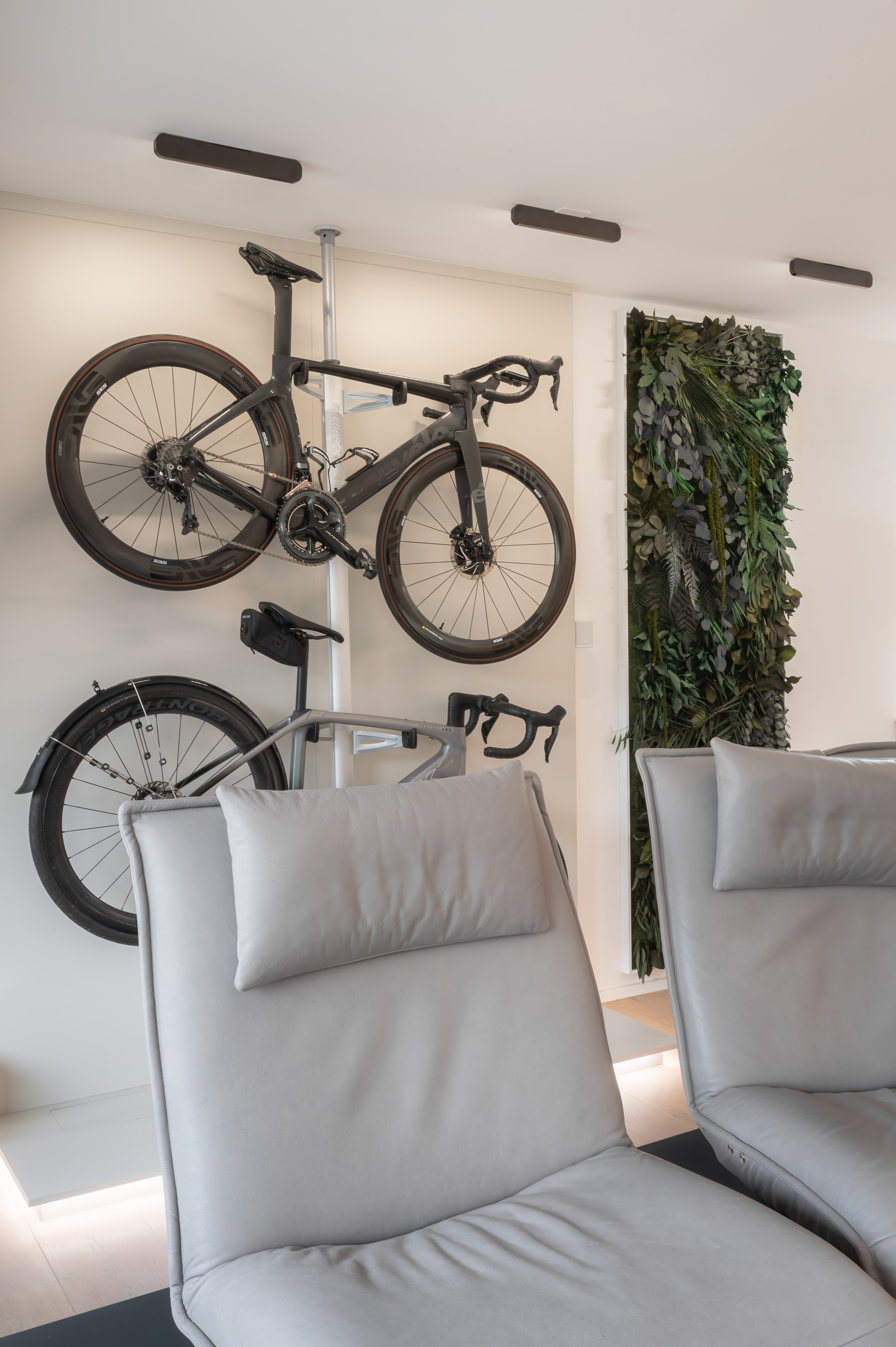 Foto: Moderne, verstellbare, graue Leder Sessel, im Hintergrund an der Wand inszenierte Rennräder mit indirekter Beleuchtung und Pflanzenwand.